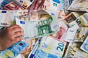 Child stealing one hundred euro banknote on more euro banknotes
