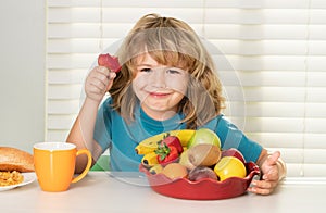 Child with strawberry, summer fruits. Child eats organic food. Healthy vegetables with vitamins. Proper kids nutrition