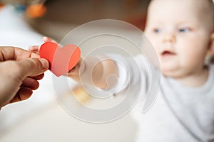 The child stretches and takes the symbol of a red heart in the hand