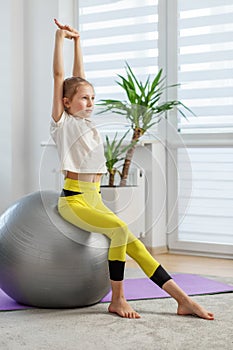 Child Stretching Arms Upwards While Seated on Ball