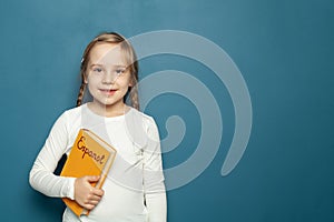 Child student girl with Spanish Espanol language book on the background of blue chalkboard