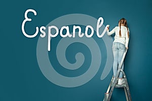 Child student girl standing on ladder and writin Spanish language on blue chalkboard