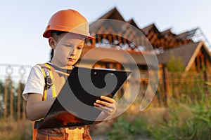 Child in a suit of an engineer is checking and inspecting the building or house before restoration, reconstruction or demolition.