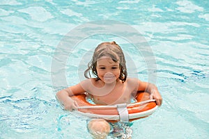 Child summer holidays. Boy having fun at aquapark. Happy kid playing with lifebuoy. Summer vacations.
