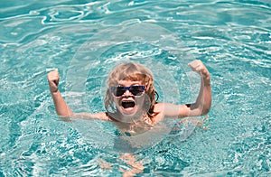 Child in summer swimming pool. Excited cute little boy in sunglasses in pool in sunny day.