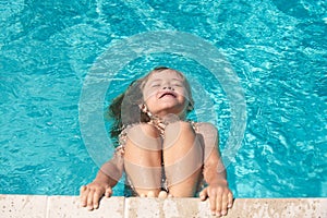 Child in summer swimming pool. Happy little kid boy playing with in outdoor swimming pool on hot summer day. Kids learn