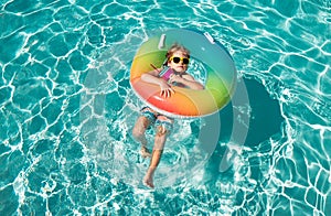 Child summer vacation. Summertime weekend. Boy in swiming pool. Happy boy on inflatable rubber circle.