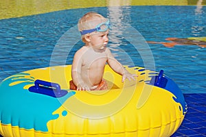 Child sunbathing, swim with inflatable toy in swimming pool