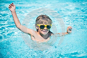 Child in sunglasses on beach. Portrait of cute kid having fun in swimming pool.