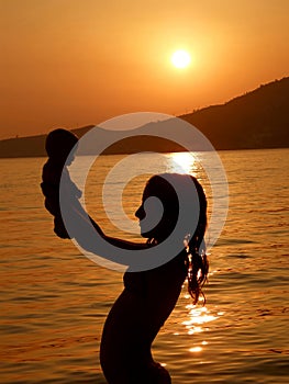 Child in sunset with baby toys on sea