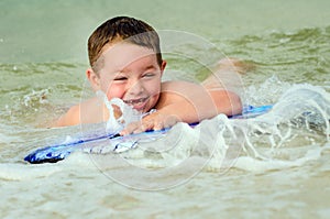 Child surfing on bodyboard at beach