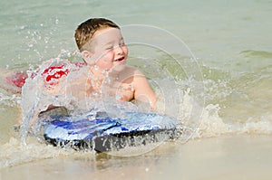 Child surfing on bodyboard at beach