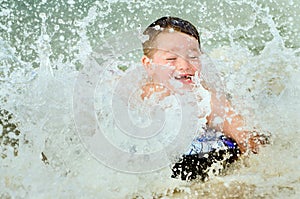 Child surfing on bodyboard at beach