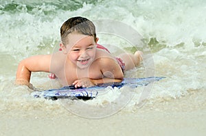 Child surfing on bodyboard at beach