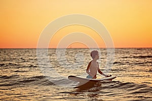 Child surfing on tropical beach. Family summer vacation in Asia. Kids swim in ocean water