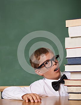 Child, surprise and portrait with stack of books in classroom for education, language learning and knowledge. Kid or