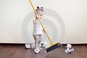 Child sweeps broom with paper bins in the apartment, household chores