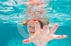 Child swim and dive underwater in the swimming pool. Summer vacation concept.