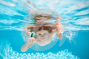 Child swim and dive underwater in the swimming pool. Water play, healthy outdoor sport activity for children.