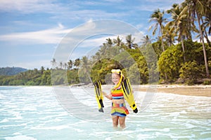 Child with swim fins snorkeling on tropical beach