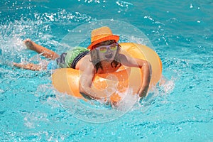 Child swim with float ring in swimming pool. Kids summer holidays and vacation concept. Happy little boy with colorful