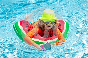 Child swim in poolside in water background. Happy kid playing with colorful swim ring in swimming pool on summer day