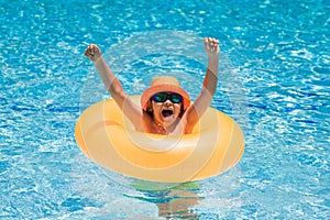 Child swim on ring floating in blue swimming pool. Inflatable ring, rest kids concept.