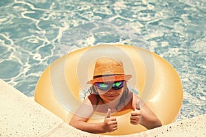 Child swim on ring floating in blue swimming pool. Inflatable ring, rest kids concept.