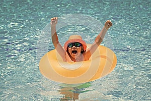 Child swim on ring floating in blue swimming pool. Inflatable ring, rest kids concept.