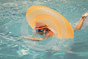 Child swim on ring floating in blue swimming pool. Inflatable ring, rest kids concept.