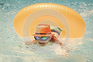 Child swim on ring floating in blue swimming pool. Inflatable ring, rest kids concept.