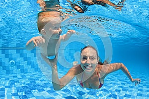 Child swimming lesson - baby with moher dive underwater in pool