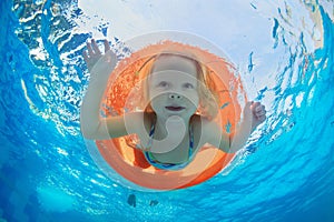 Child swimming on orange inflatable tube in pool