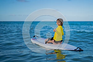 Child swimming on paddle board. Water sports, active lifestyle. Kid paddling on a paddleboard in the ocean. Child Paddle