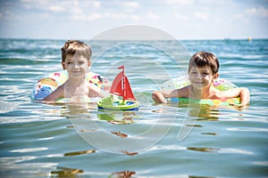 Child in swimming pool floating on toy ring. Kids swim. Colorful rainbow float for young kids. Little boy having fun on family