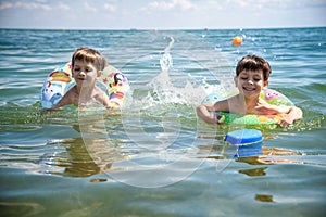 Child in swimming pool floating on toy ring. Kids swim. Colorful rainbow float for young kids. Little boy having fun on family