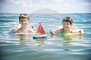 Child in swimming pool floating on toy ring. Kids swim. Colorful rainbow float for young kids. Little boy having fun on family