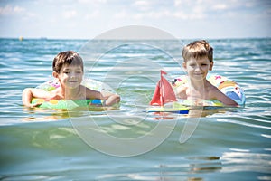 Child in swimming pool floating on toy ring. Kids swim. Colorful rainbow float for young kids. Little boy having fun on family