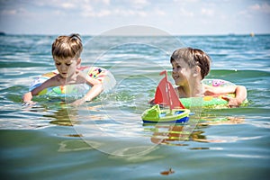 Child in swimming pool floating on toy ring. Kids swim. Colorful rainbow float for young kids. Little boy having fun on family