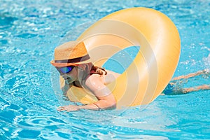 Child in swimming pool on inflatable ring. Kid swim with orange float. Kids beach fun.