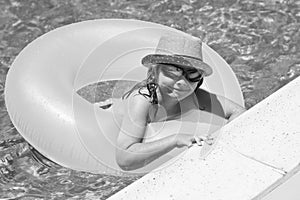 Child in swimming pool on inflatable ring. Kid swim with orange float. Kids beach fun.