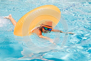 Child in swimming pool on inflatable ring. Kid swim with orange float. Kids beach fun.