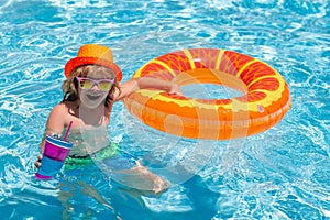 Child in swimming pool on inflatable ring. Kid swim with orange float. Summer kids cocktail. Water toy, healthy outdoor
