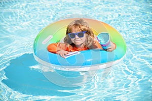 Child in swimming pool on inflatable ring. Little boy learning to swim with float. Water toy for toddler. Healthy