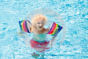 Child in swimming pool. Kid with float armbands