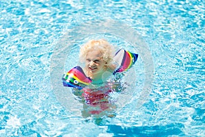 Child in swimming pool. Kid with float armbands