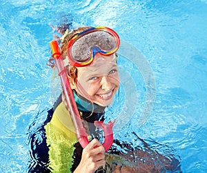 Child in swimming pool learning snorkeling.