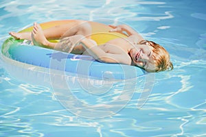 Child in swimming pool playing in water. Vacation and traveling with kids. Children play outdoors in summer. Kid with