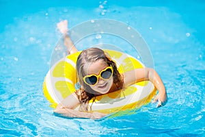 Child in swimming pool on ring toy. Kids swim