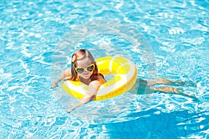 Child in swimming pool on ring toy. Kids swim